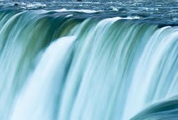 Blue green water racing over the edge of Niagara Falls, Canada