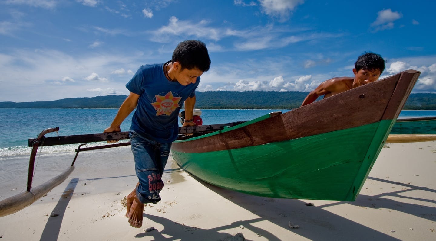 Two men haul a canoe onto the beach on a small island in Central Sulawesi. 