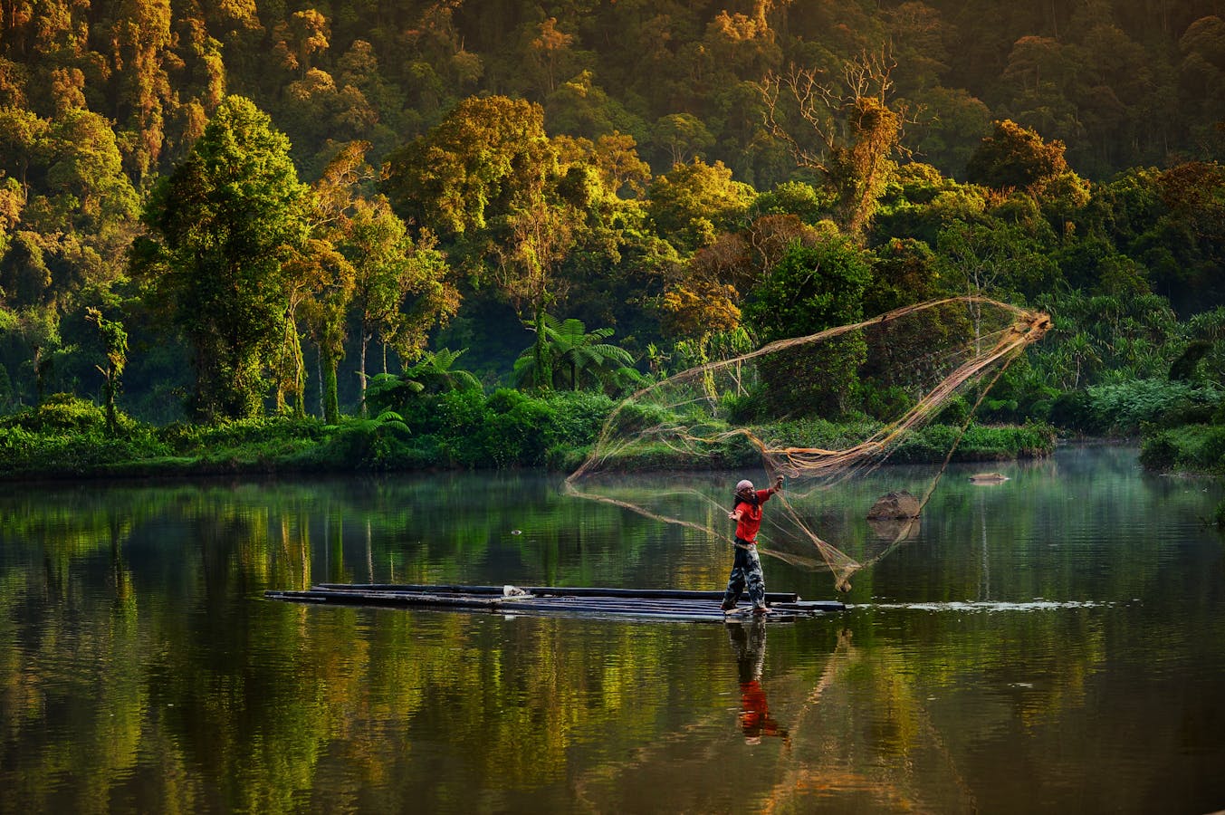 A man in West Java, Indonesia fishing in the lake using a traditional net.