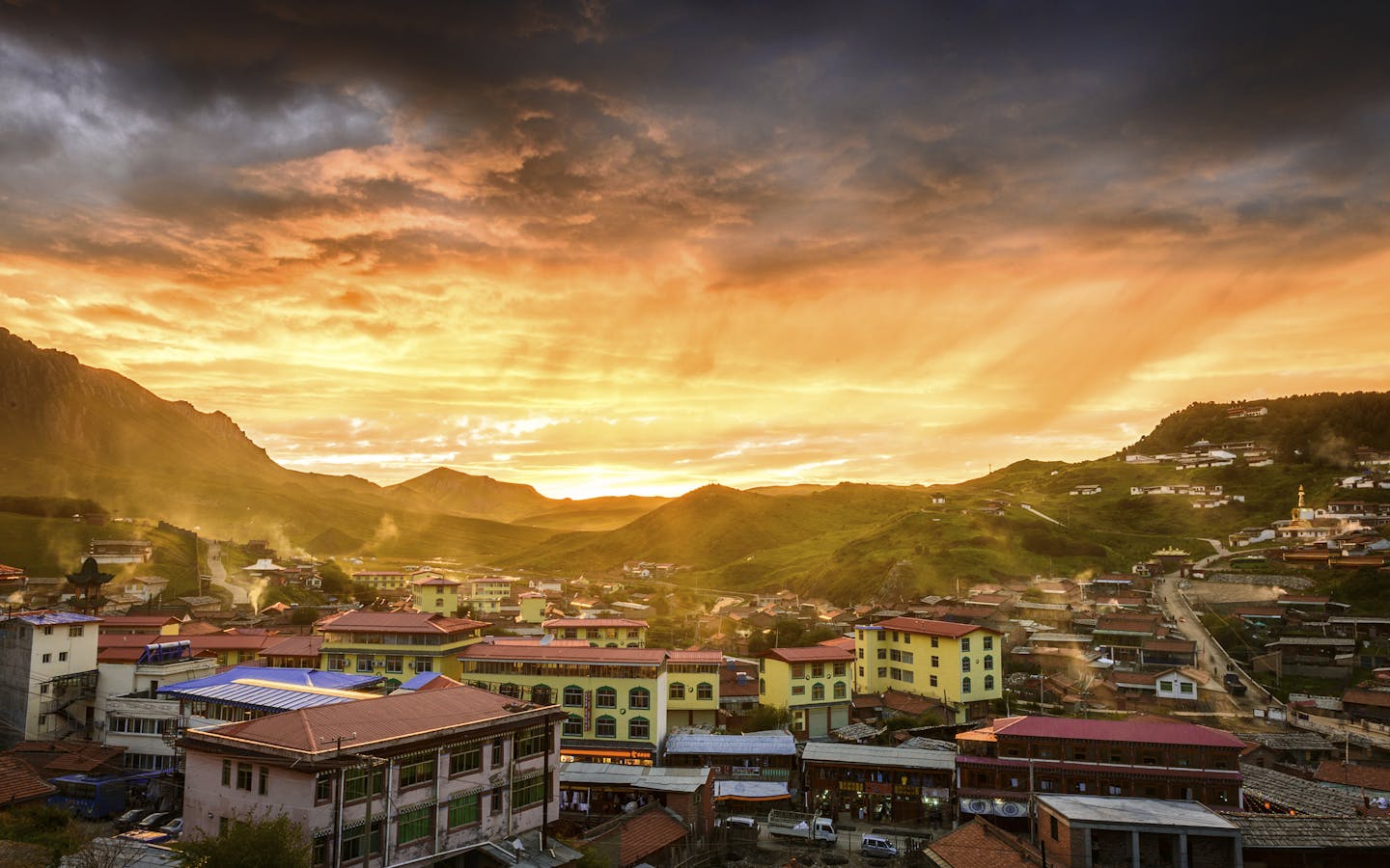 Skyline of a small rural town with rolling hills in Tibet during sunset.