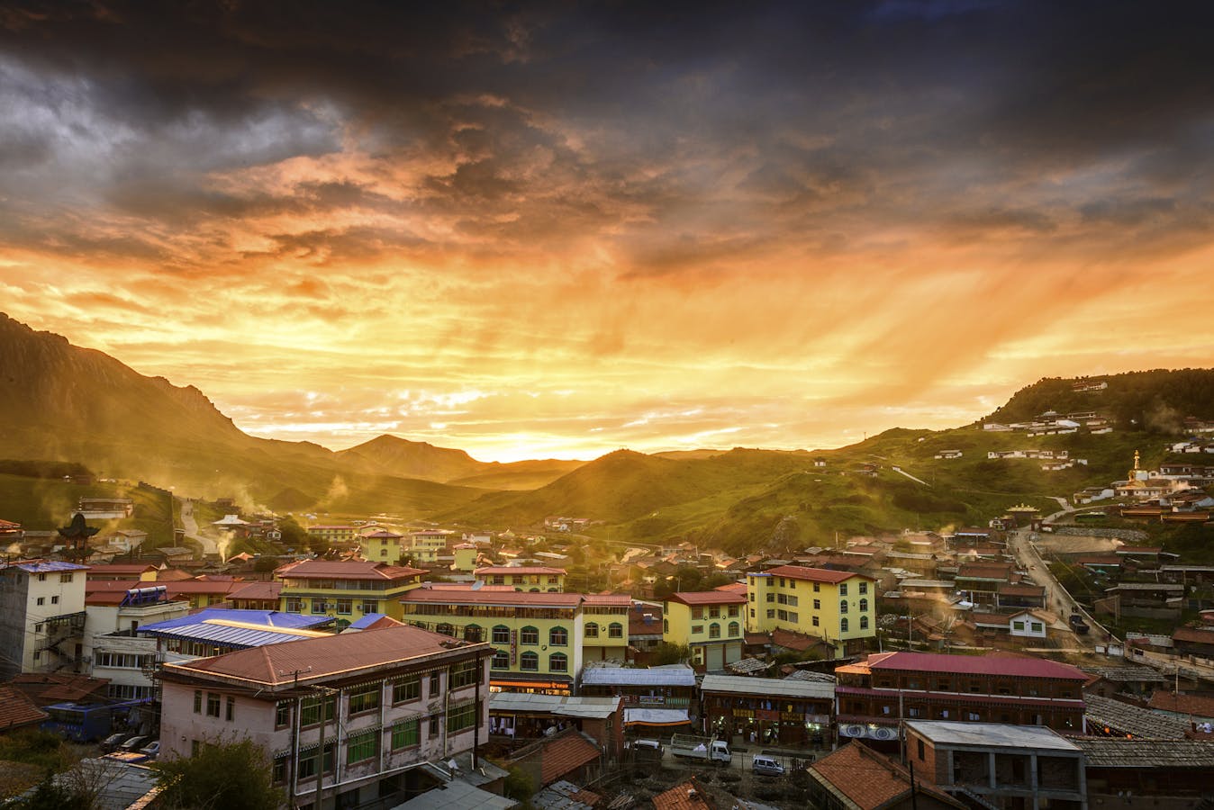 Skyline of a small rural town with rolling hills in Tibet during sunset.